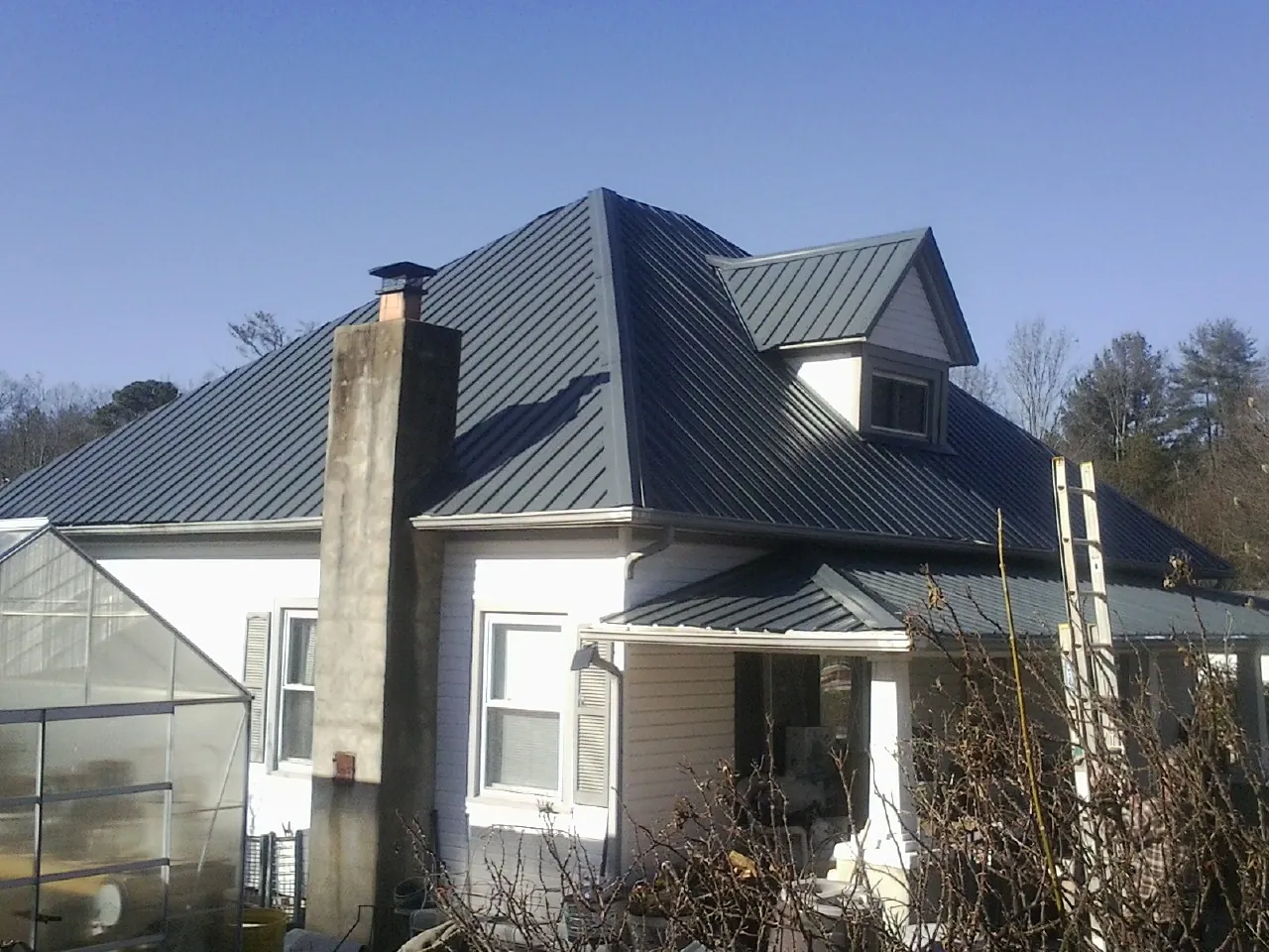 Dark blue standing seam metal roof on a white farmhouse with dormer — Slate & Tile Roof Repair by Roofing Brothers in Curlew