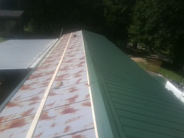Old rusted panels beside newly installed green metal roofing — Wind Damage Roof Repair by Roofing Brothers in Curlew