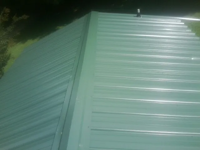 New green metal panels meeting at the ridge of a roof — Flat Roof Repair work by our crew in Curlew
