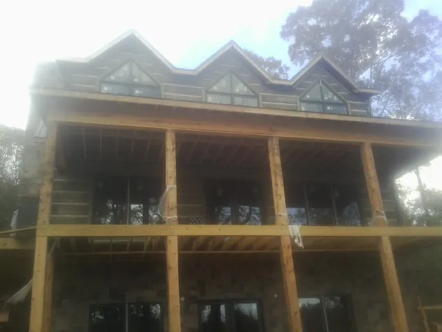 Dormers and porch framing on a large log home under construction — Roof Coating work by our crew in Curlew