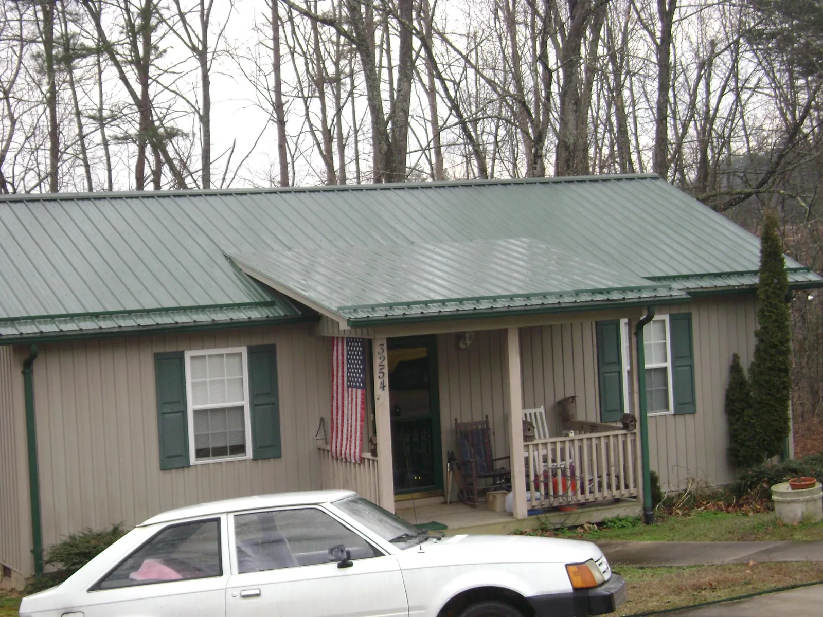 Green metal roof and front porch on a tan sided cottage in Curlew