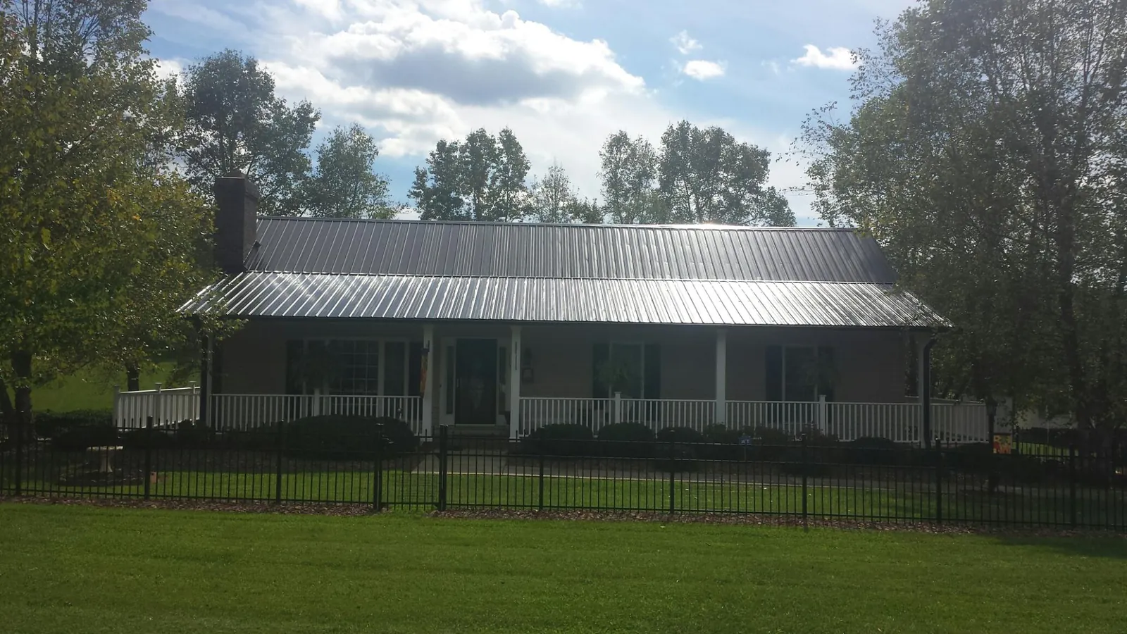 Gray metal roof on a brick ranch with a full width front porch — Gutter Guard Installation work by our crew in Curlew