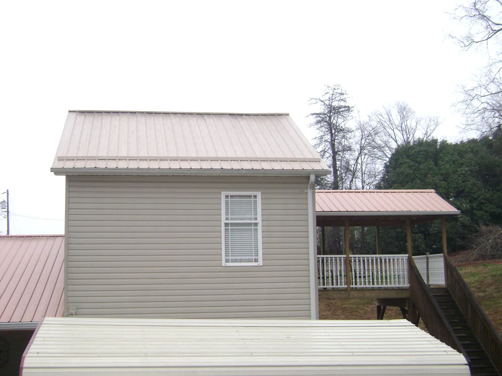 Tan metal roofs on a two story addition and attached porch, from a Roof Replacement job in Curlew