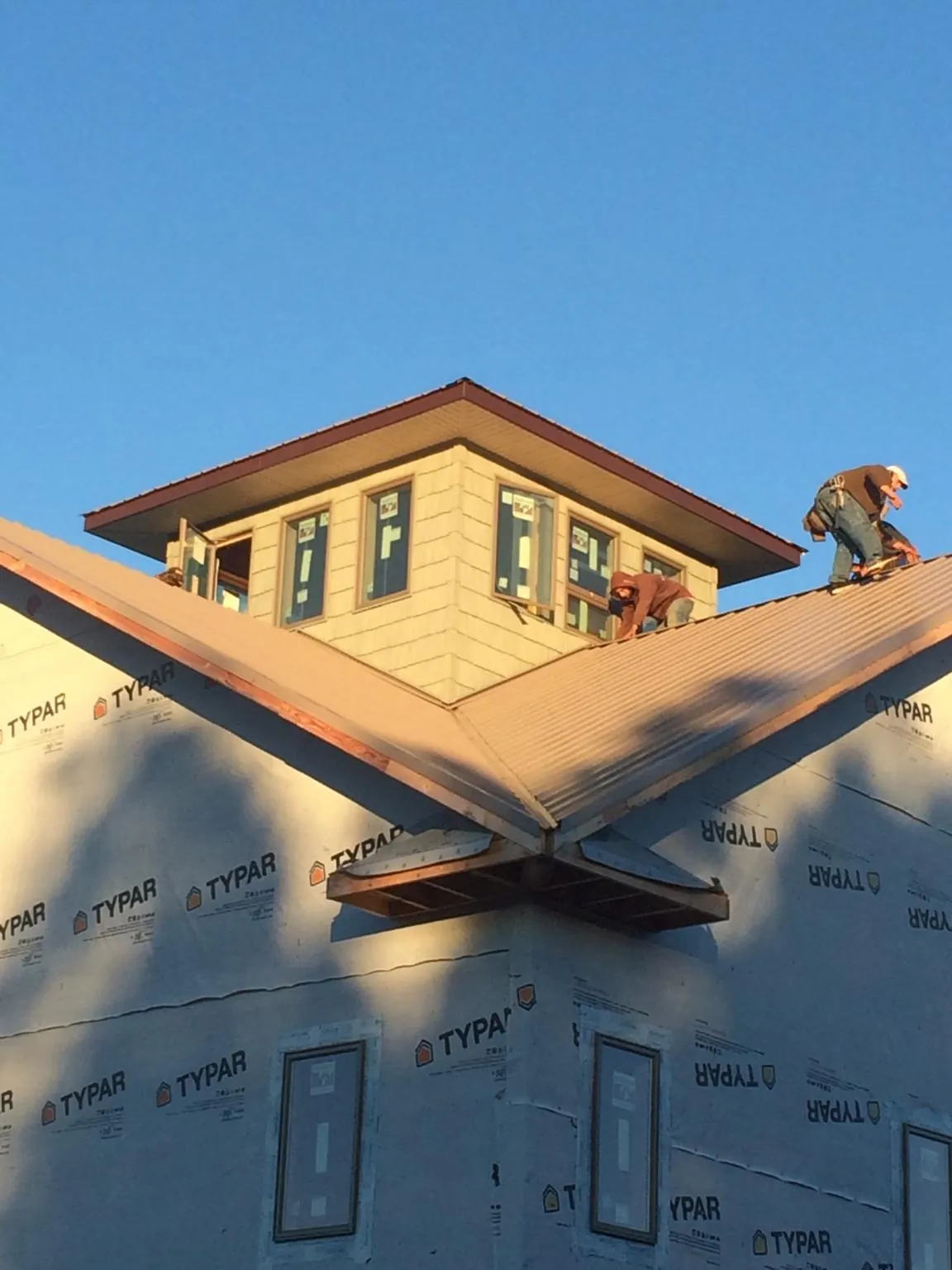 Roofers working around a rooftop cupola on a new metal roof at sunset — Roof Waterproofing in Curlew by Roofing Brothers